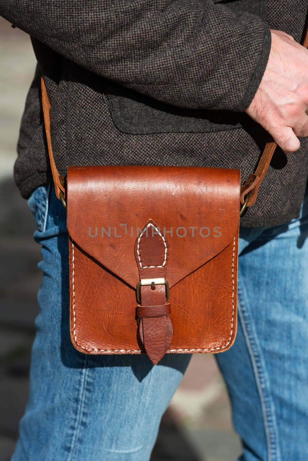 close-up photo of light brown messanger leather bag on mans shoulder by Ashtray25