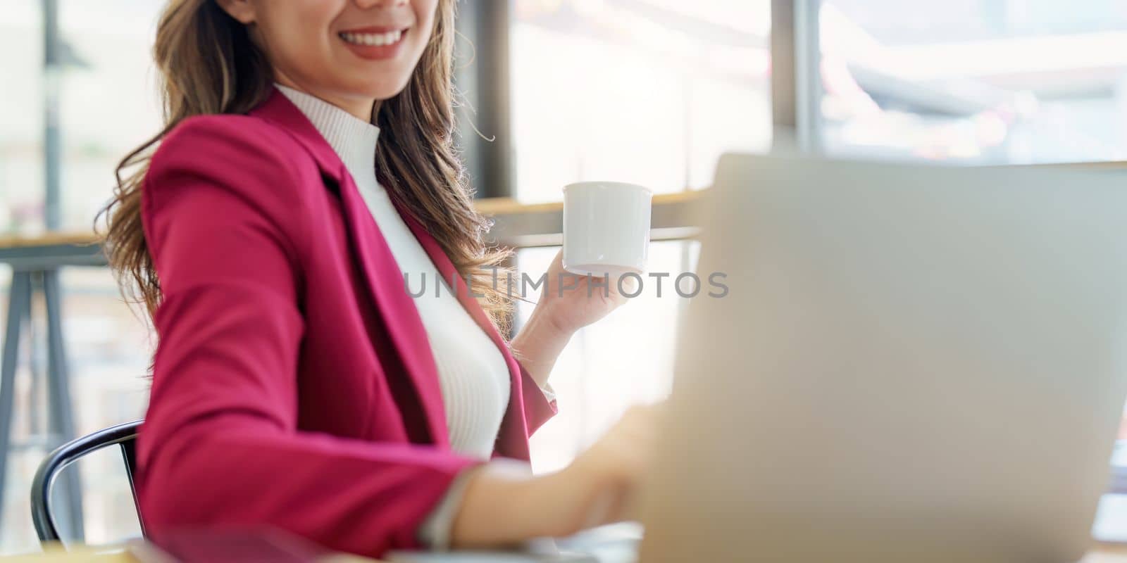 Smiling asian business woman with laptop computer in office. Woman in suit at office.