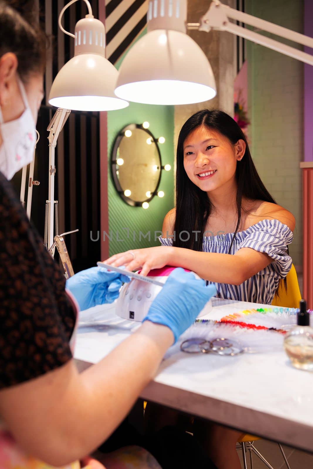 young asian woman filing the nails during her manicure treatment at the beauty salon, wellness and hands care concept