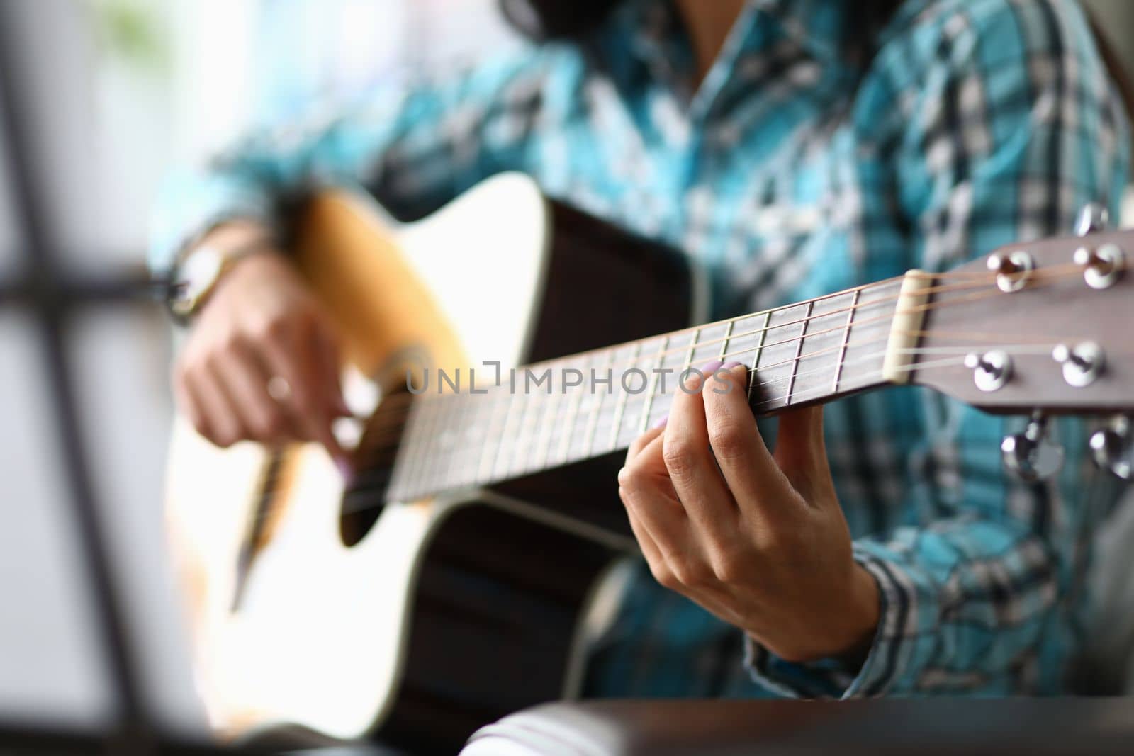 Woman hands playing guitar closeup. Learning to play acoustic guitar concept