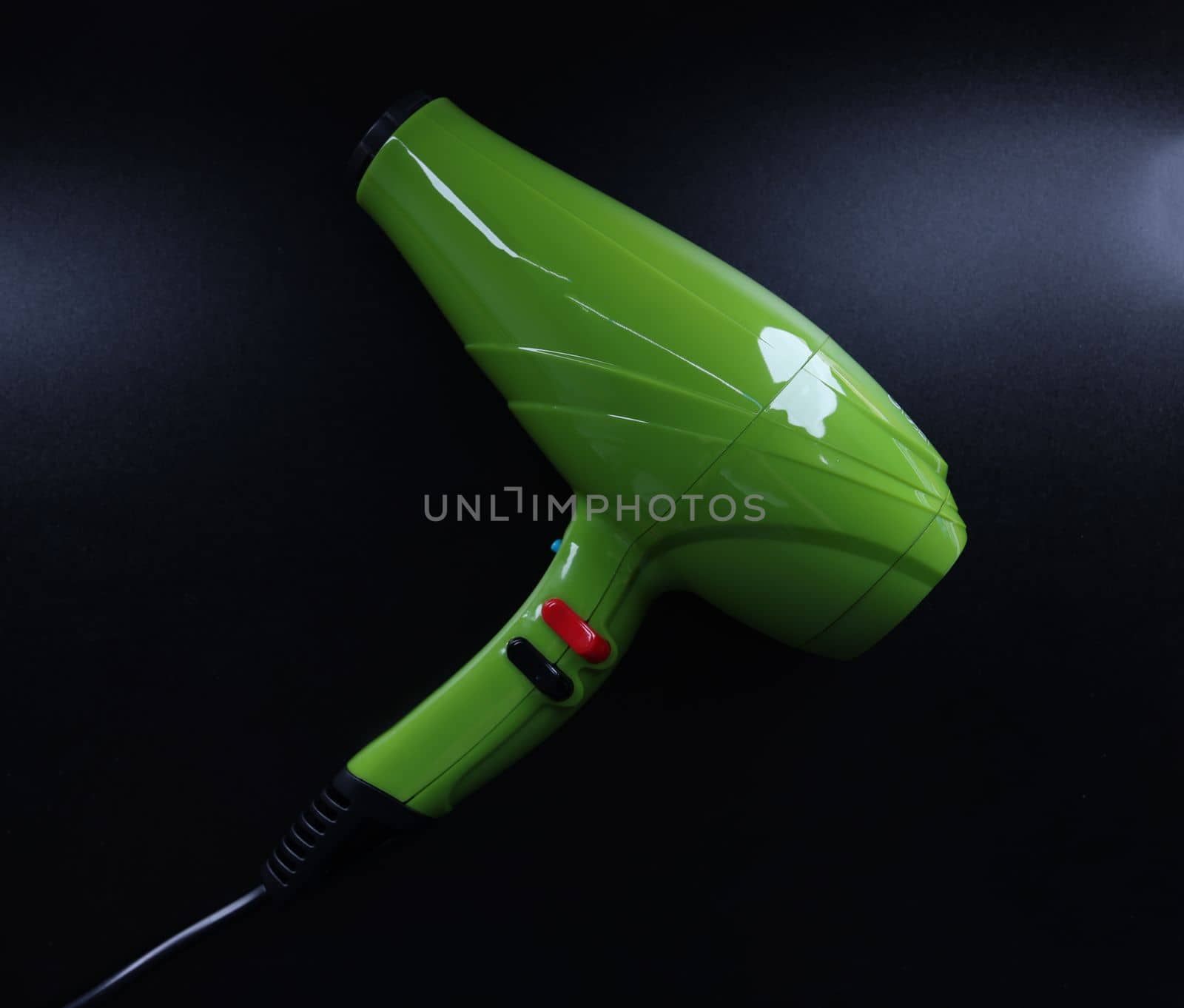 Bright green background on black background. Reliable hair dryer for home use by kuprevich
