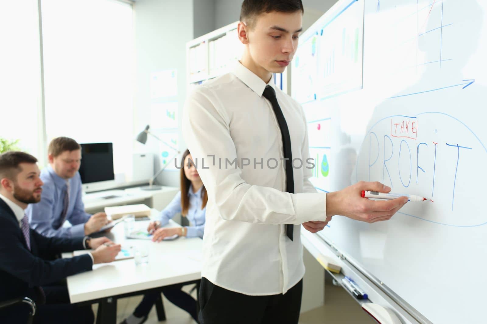 Confident business coach make presentation and profits in a business to group of workers. Team leader explaining chart on blackboard
