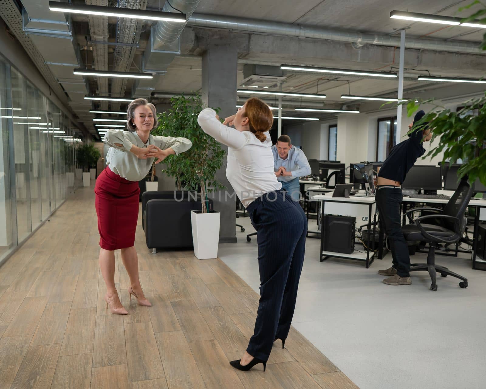 Four office workers warm up during a break. Employees do fitness exercises at the workplace. by mrwed54