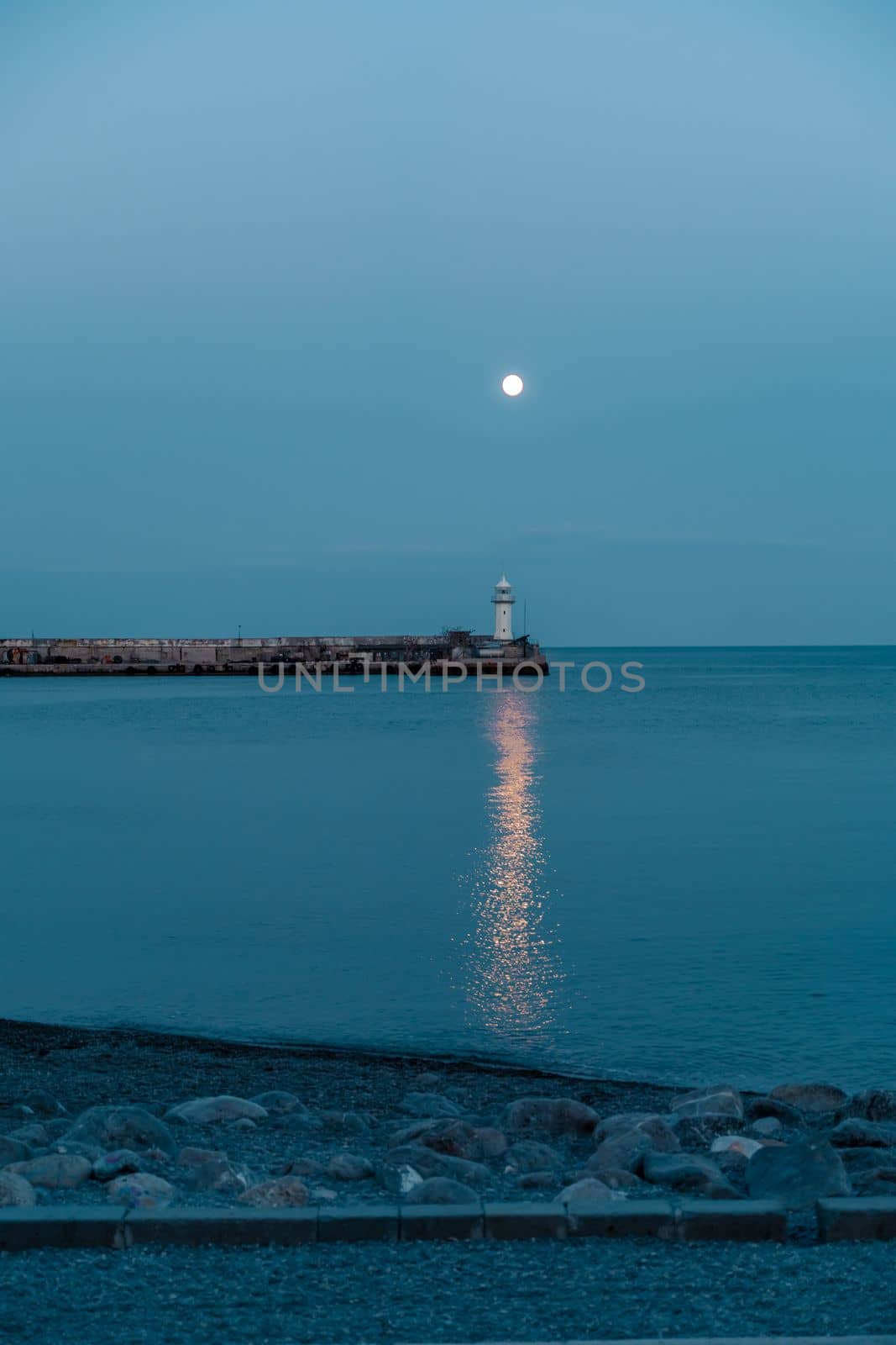 The full moon rises to the lighthouse, the moon path is not the sea