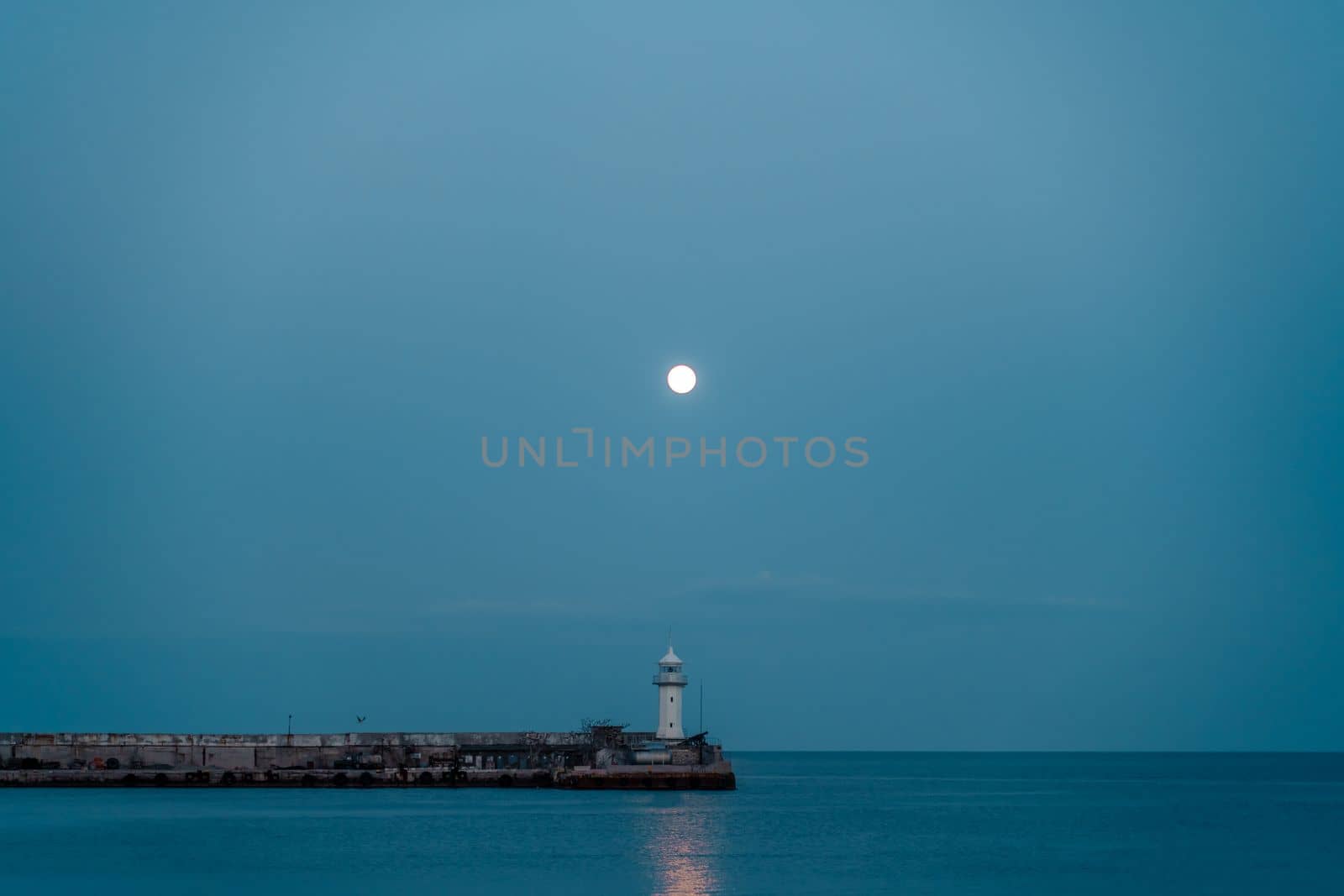 The full moon rises to the lighthouse, the moon path is not the sea. by Matiunina