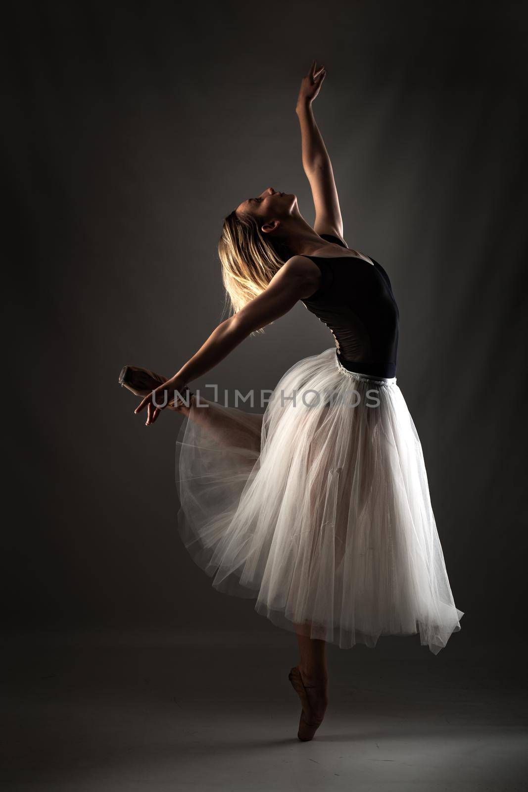 ballerina with a white dress and black top posing on gray background