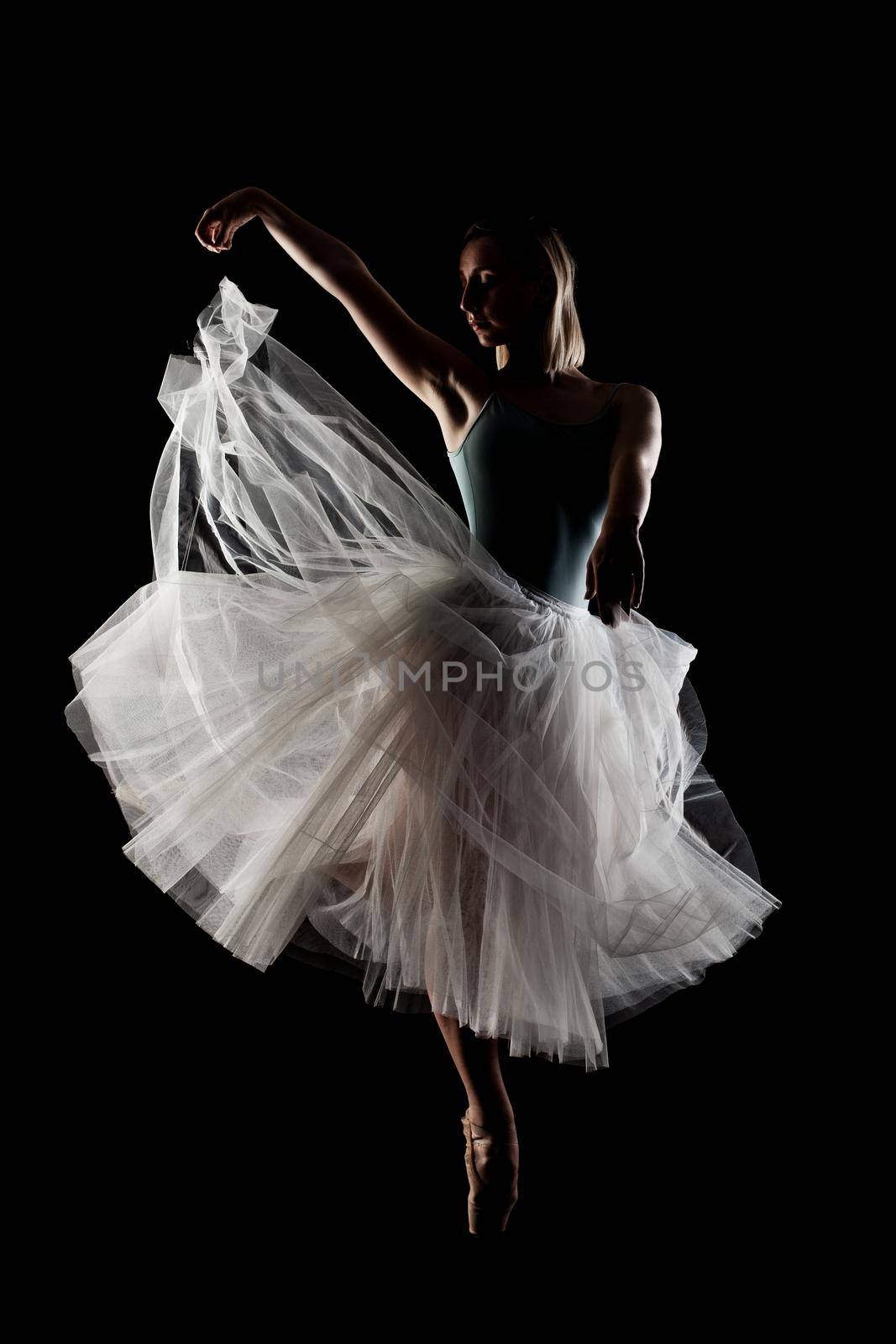 ballerina with a white dress and black top posing on black background