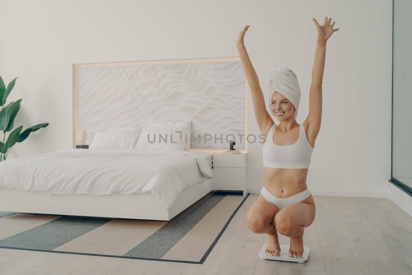 Young satisfied beautiful lady in perfect shape squatted on scales by vkstock