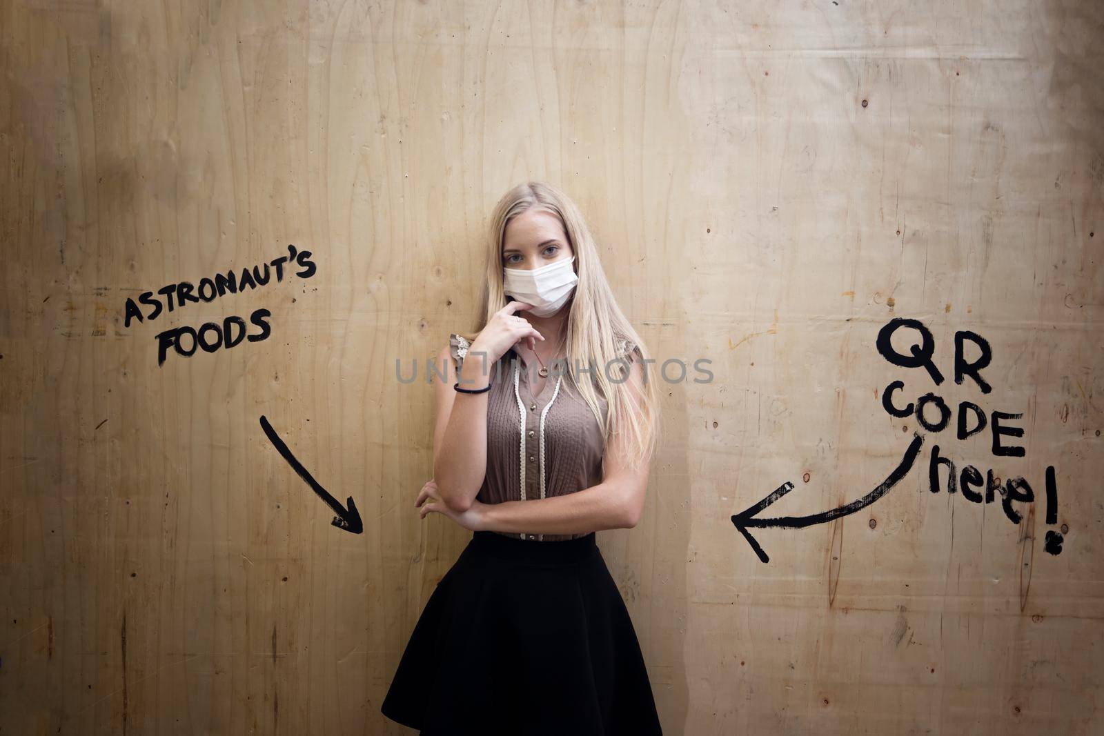 Portrait of smiling woman with mask against wall.