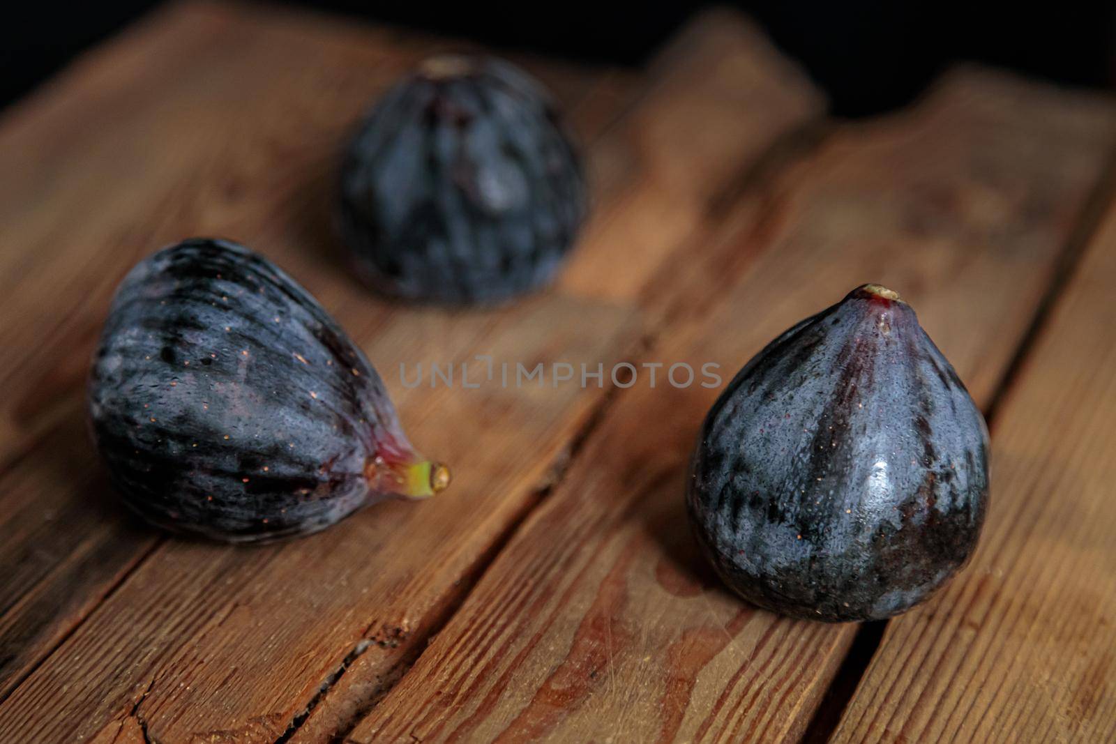 Fresh purple figs on a wooden background from old boards. Raw exotic figs. Low key
