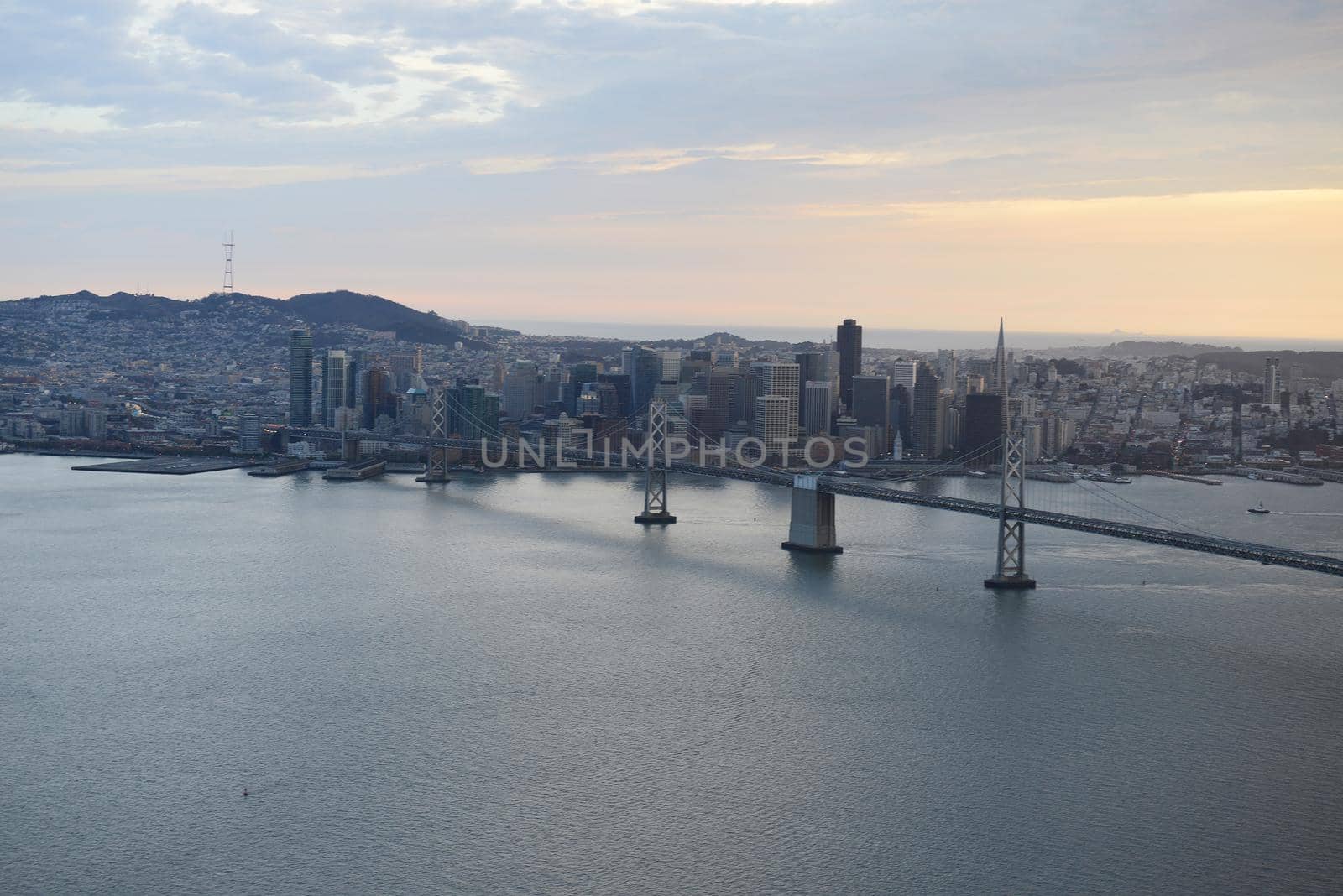 an aerial view of bay bridge near san francisco downtown during sunset, taken from a helicopter 