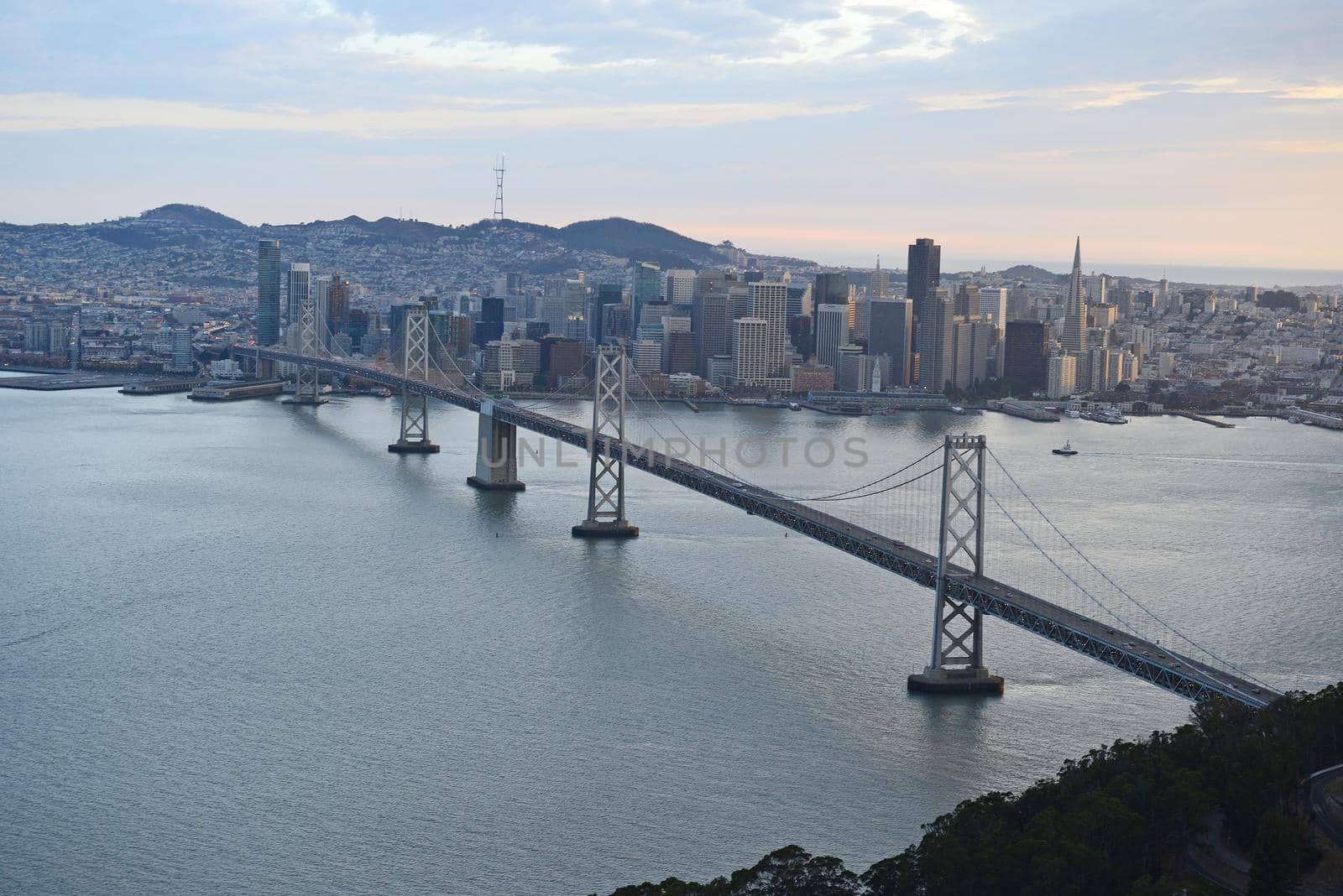 an aerial view of bay bridge near san francisco downtown during sunset, taken from a helicopter 