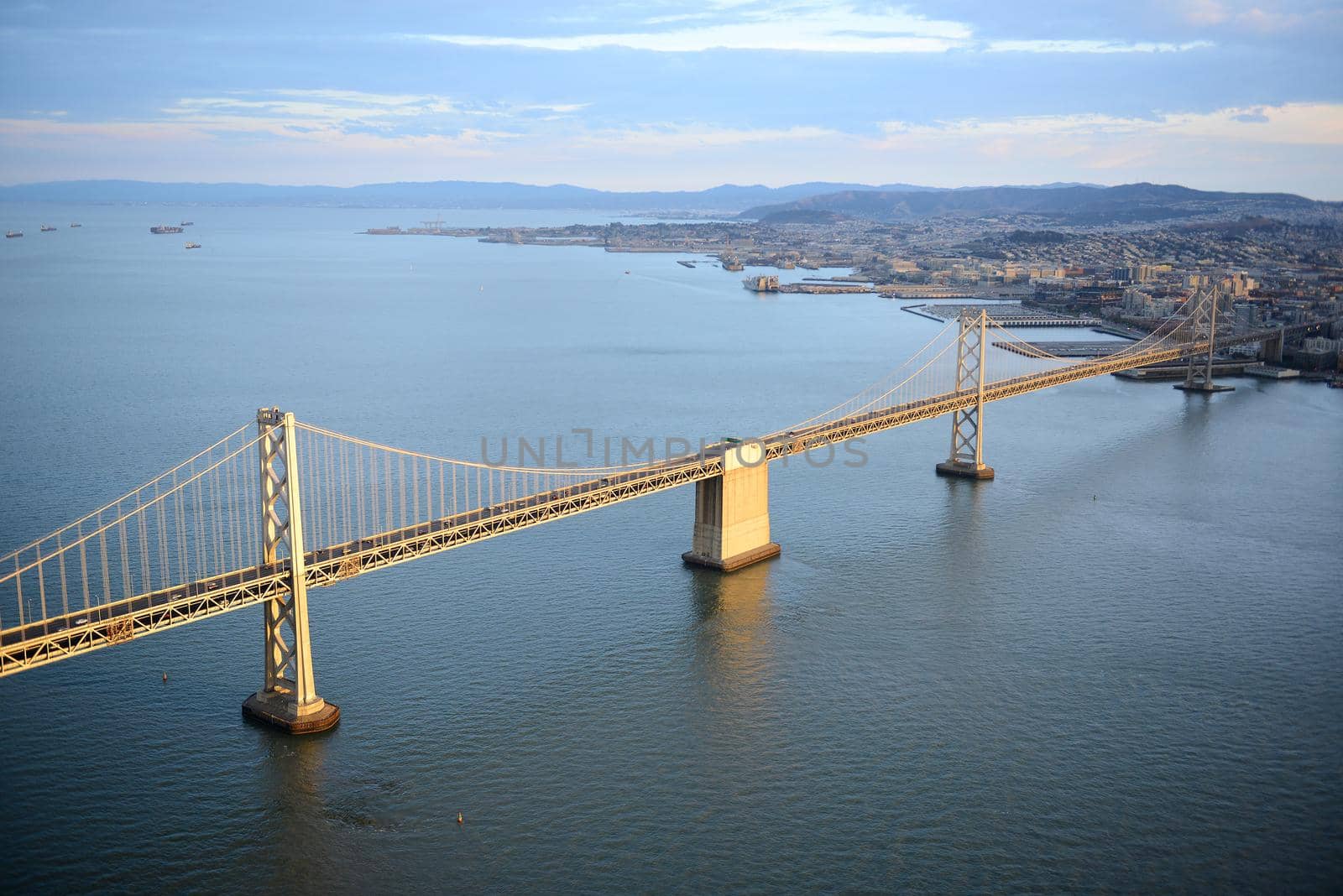 an aerial view of bay bridge near san francisco downtown during sunset, taken from a helicopter 