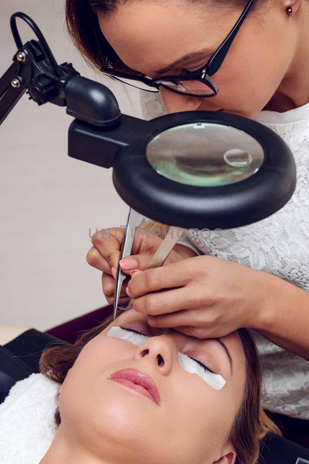 Beautician applying extended eyelashes to model at the beauty salon.