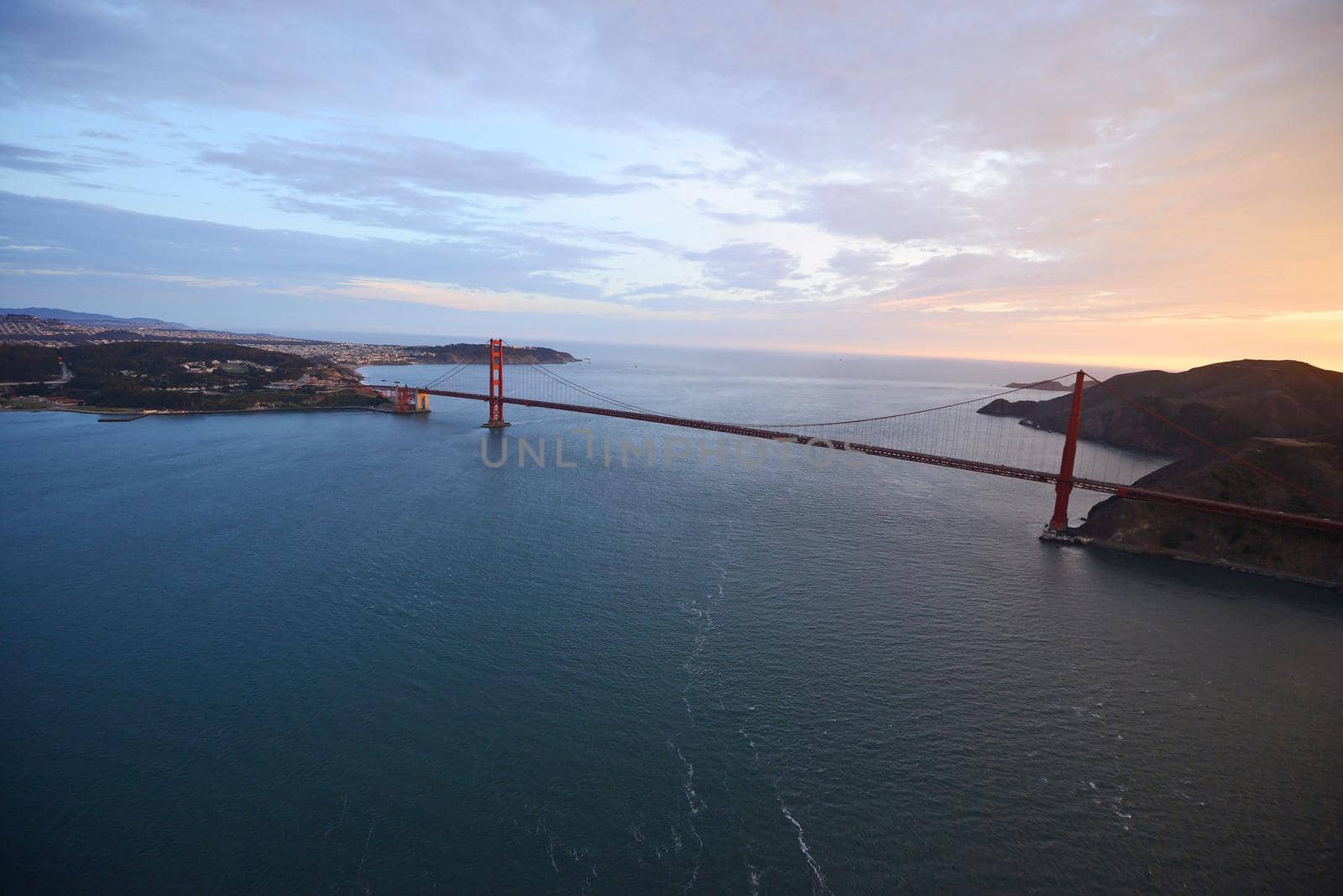 an aerial view of golden gate bridge in san francisco during sunset, taken from a helicopter