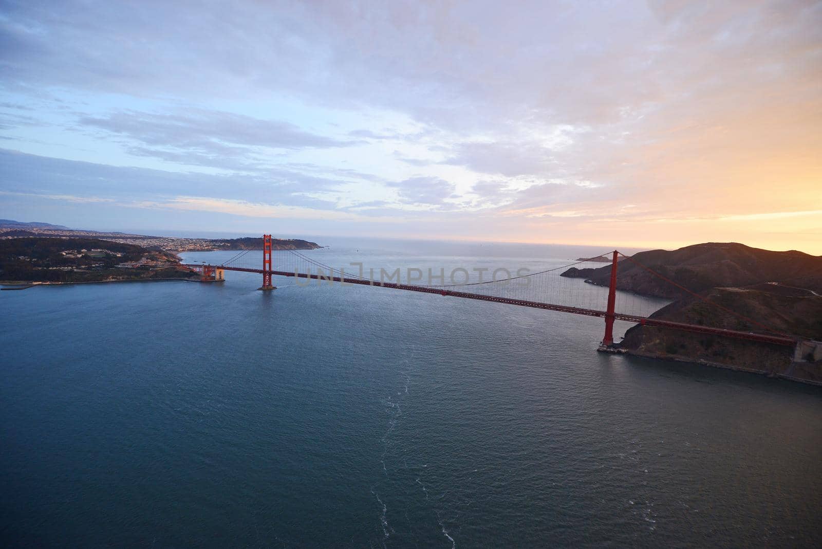 an aerial view of golden gate bridge in san francisco during sunset, taken from a helicopter