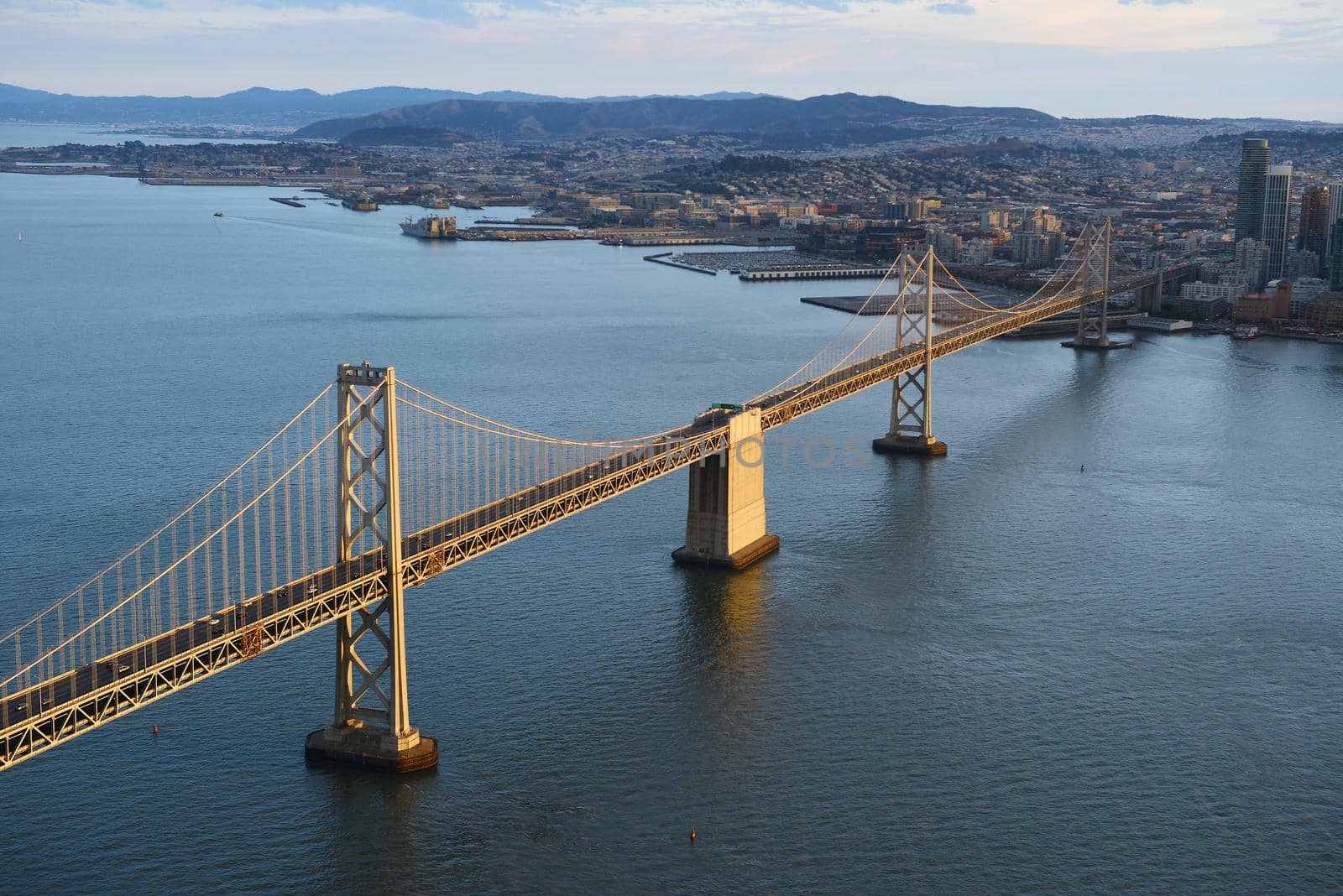 an aerial view of bay bridge near san francisco downtown during sunset, taken from a helicopter 