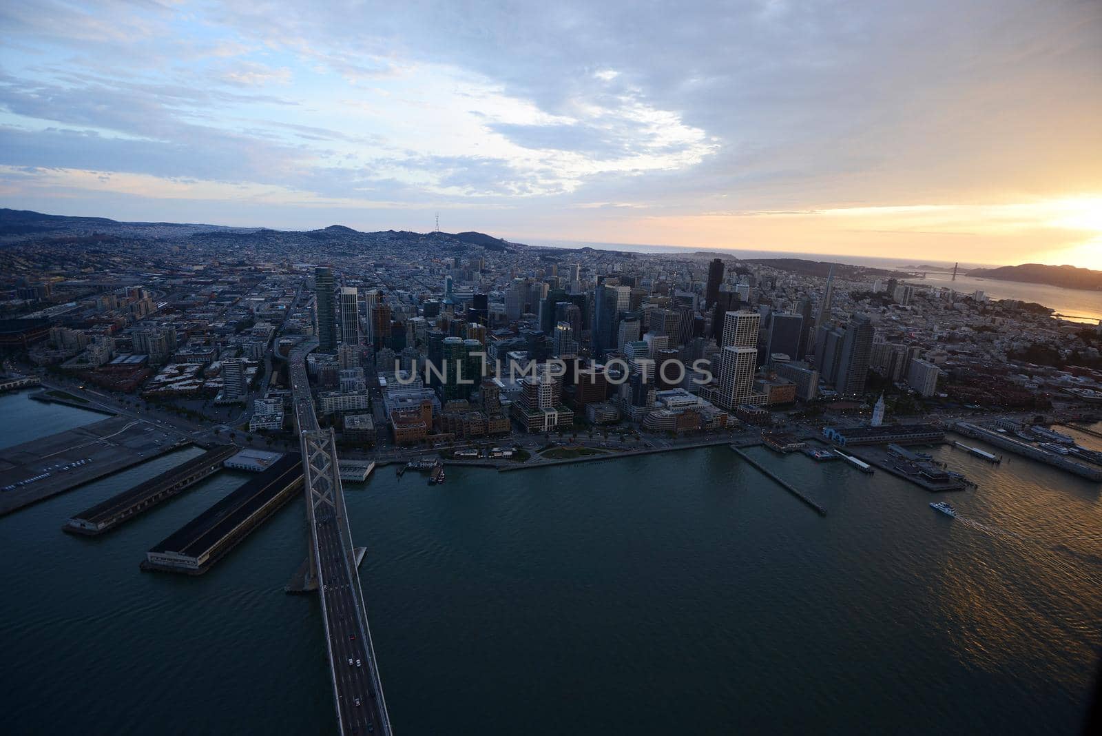 an aerial view of bay bridge near san francisco downtown during sunset, taken from a helicopter 