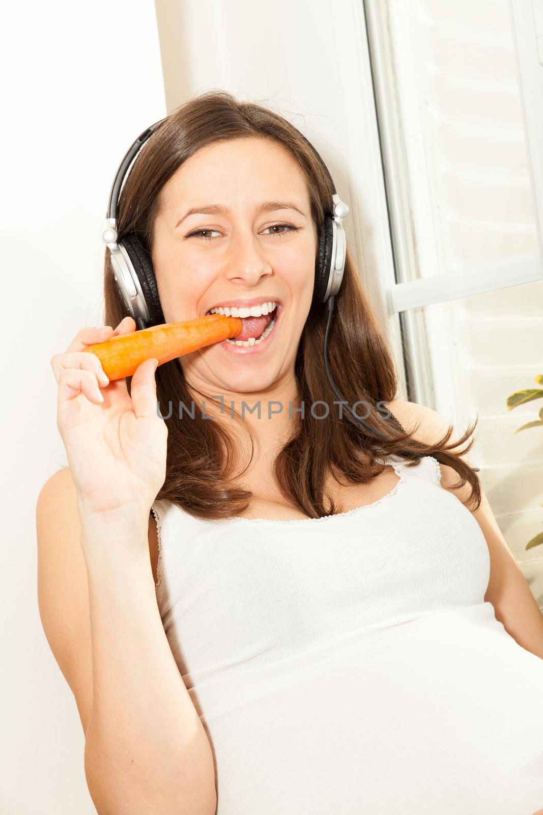 pregnant woman eat a carrot and listening to music