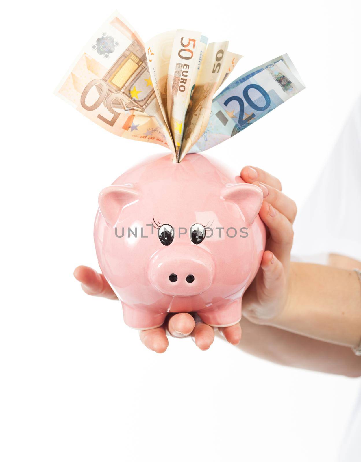 A woman shows a piggy bank full of European banknotes