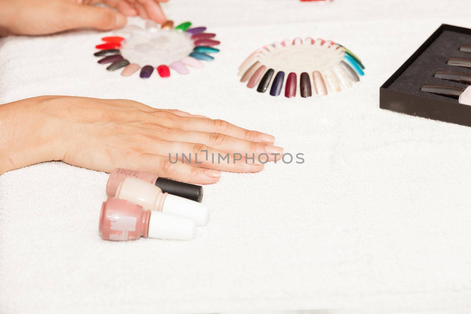 Hands of a woman who chooses the color of her nail polish