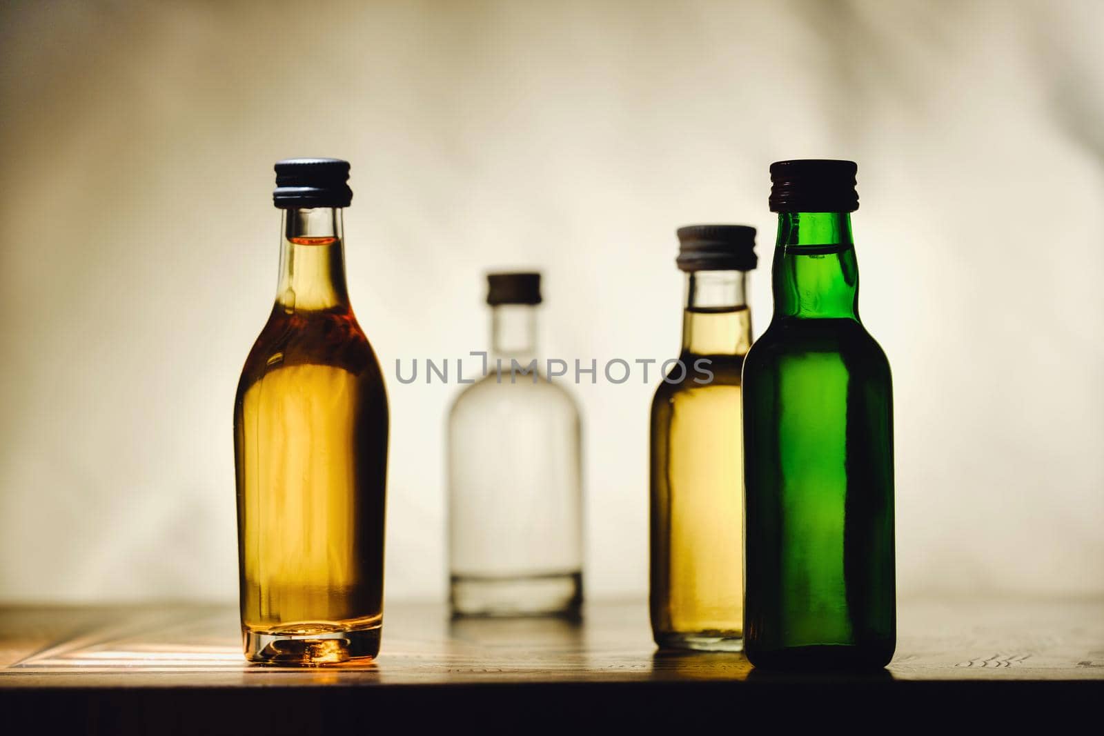 different alcohol bottles are on the table on a light background.