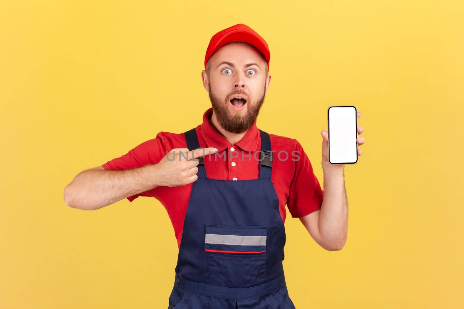 Surprised repairman pointing finger at smartphone with empty display, online service order app. by Khosro1