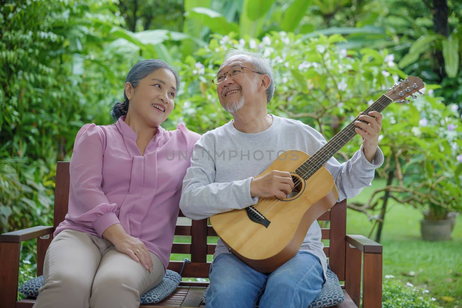 senior couple elderly man playing the guitar while his wife is singing together by Sorapop