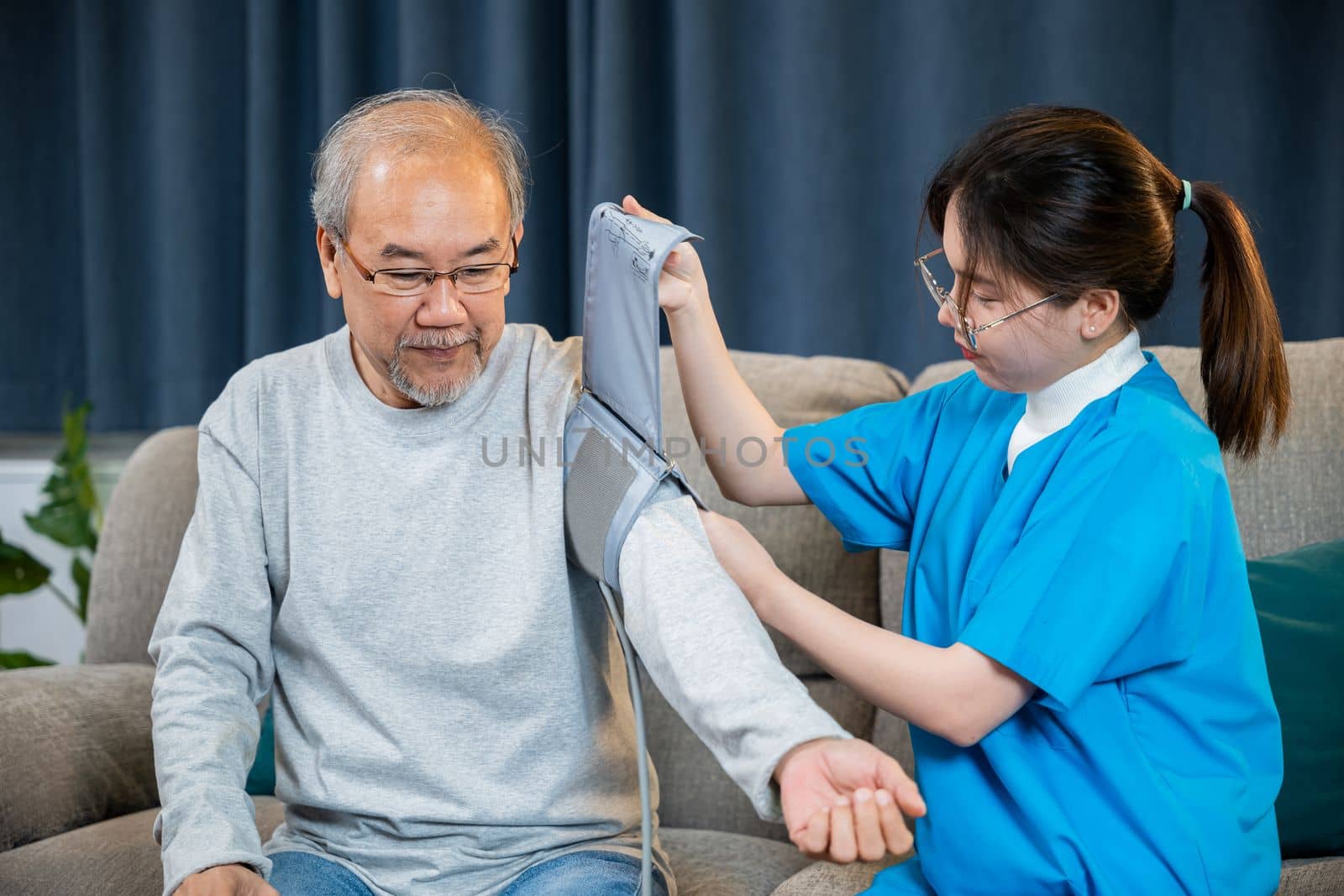 Asian nurse visit patient senior man at home she measuring arterial blood pressure on arm in living room, Doctor woman examine do checking old man client heart rate with pulsimeter monitor, Healthcare