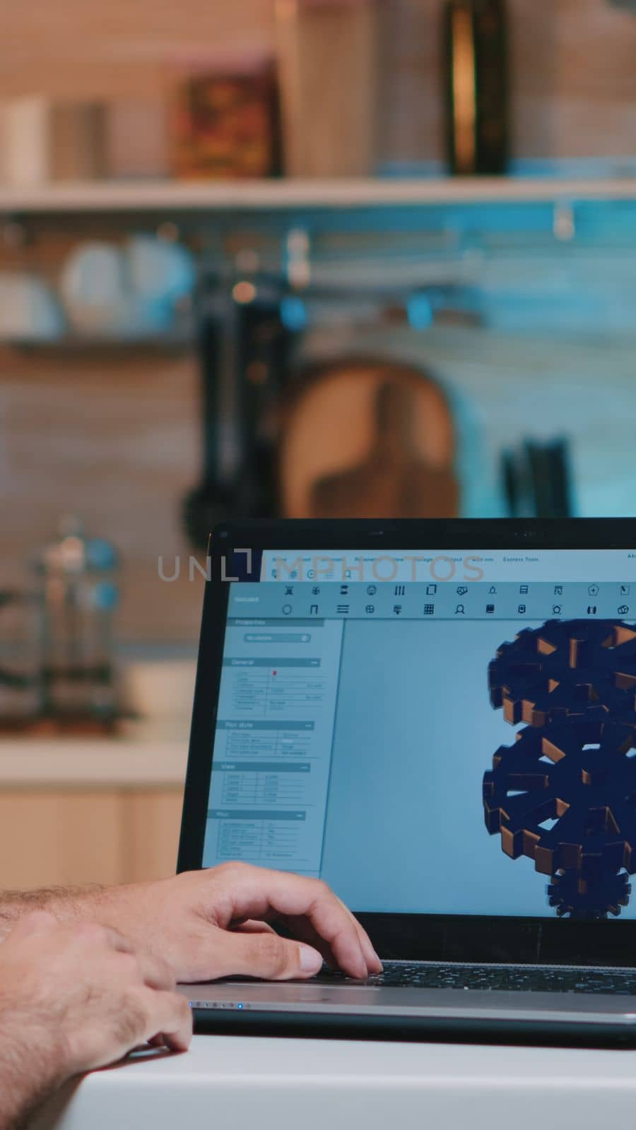 Man architect with wireless headset using laptop while working at home at night sitting in the kitchen. Industrial employee studying prototype idea on personal computer showing cad software on display