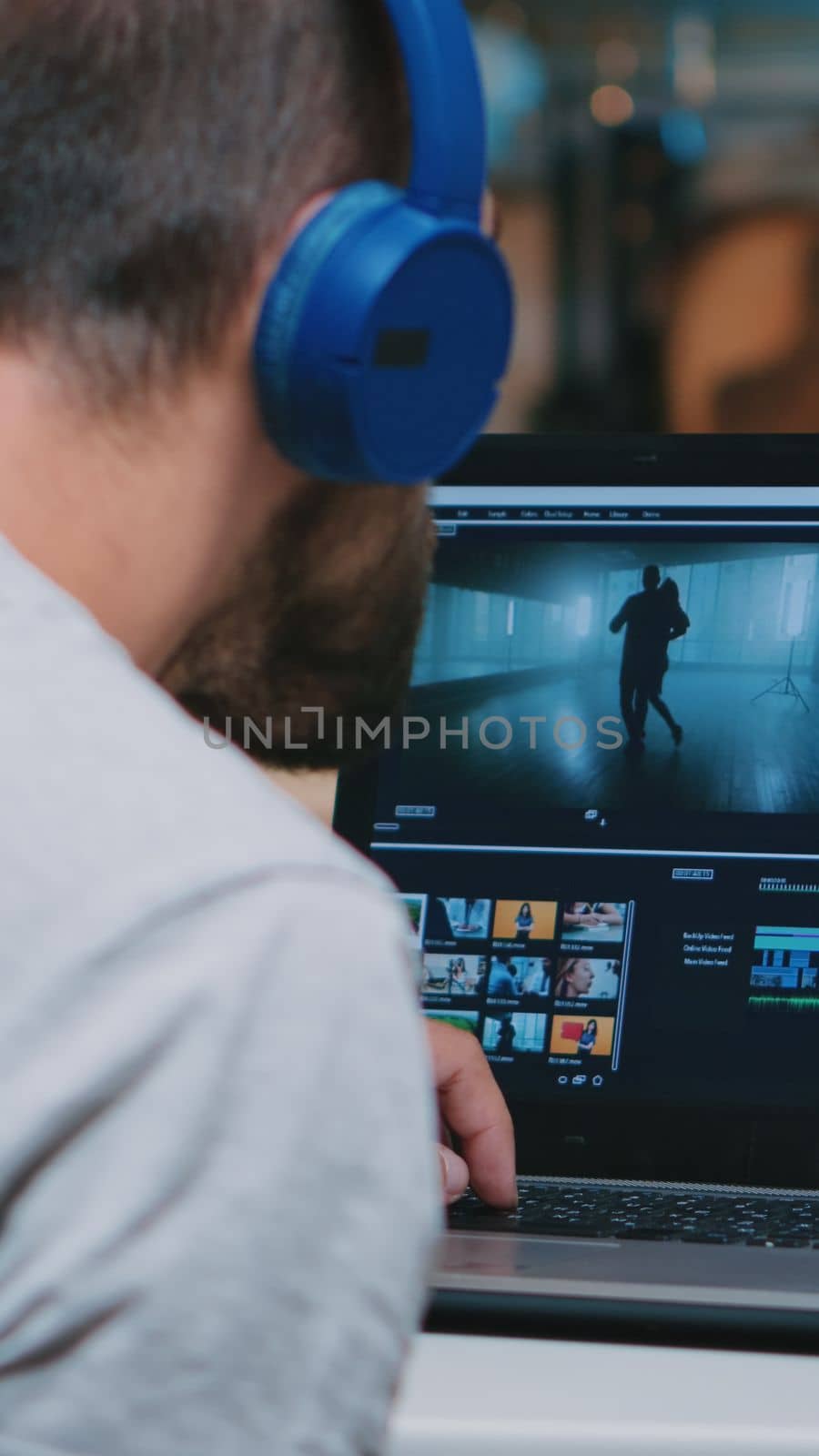 Videographer working on professional laptop from home, editing video and audio footage at night. Employee processing film montage on professional laptop sitting on desk in modern kitchen in midnight