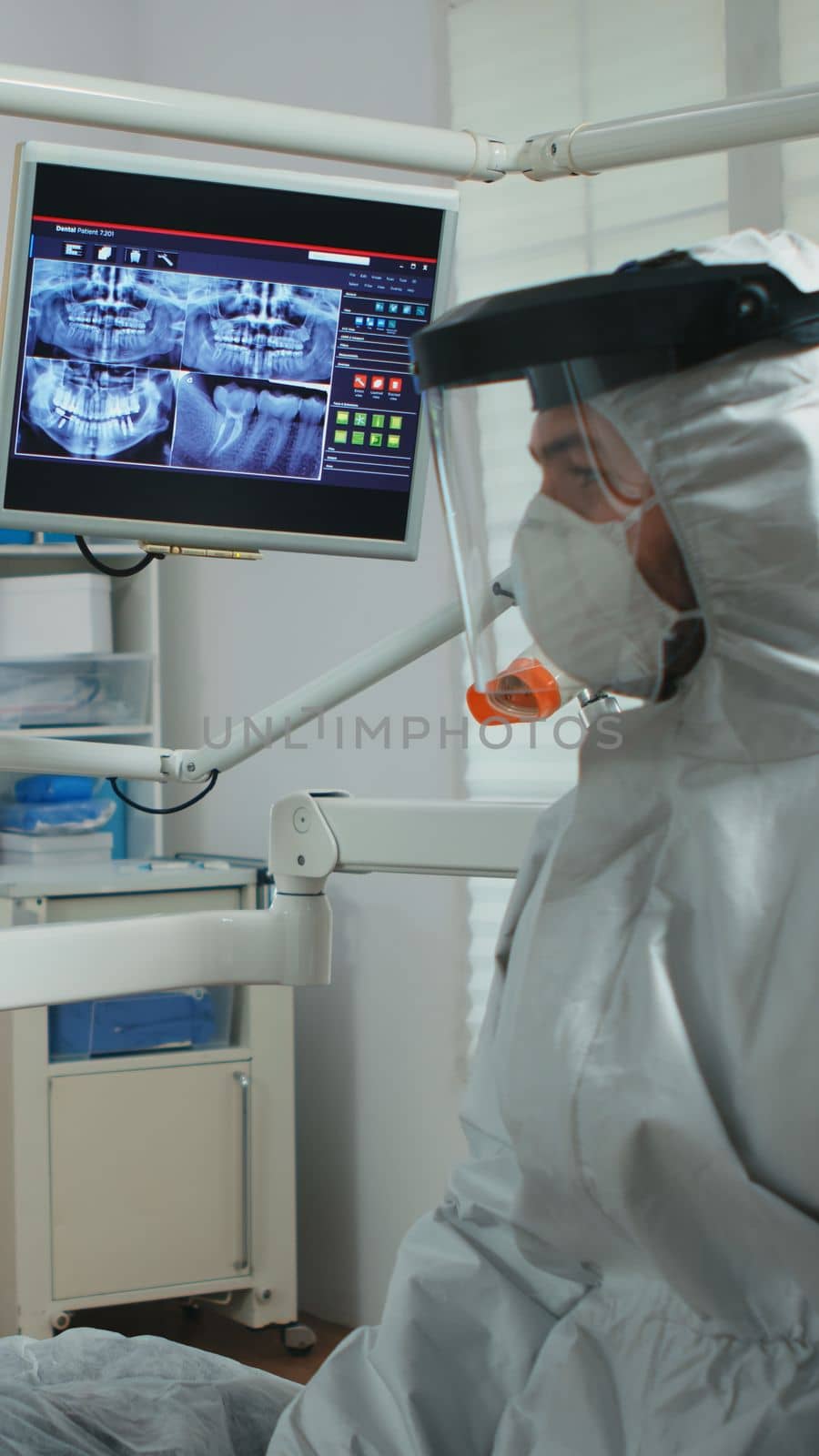 Doctor with face shield pointing on stomatological monitor by DCStudio