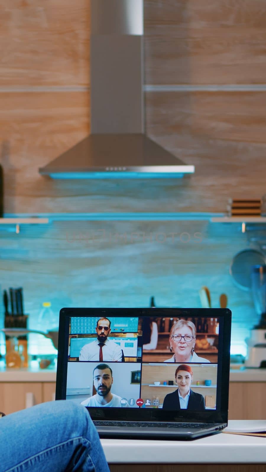 Businesswoman on video conference working remotely from home sitting in the kitchen late at night. Lady using modern technology network wireless talking on virtual meeting at midnight doing overtime