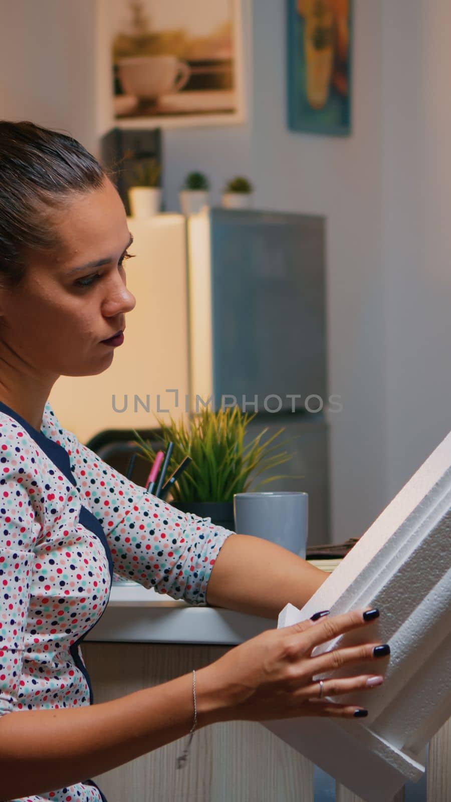 Freelancer architect working in 3D software to elaborate buildings design sitting at kitchen desk at night. Engineer artist creating and studying in office holding scale model, determination, career.
