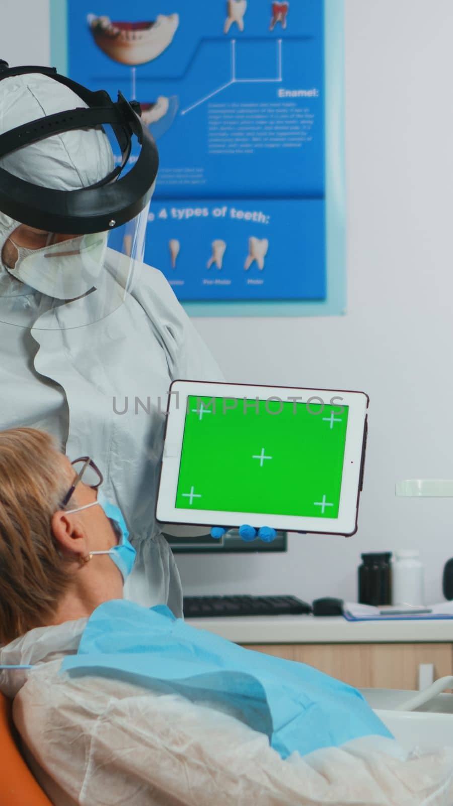 Dentist with face shield pointing at green screen display by DCStudio