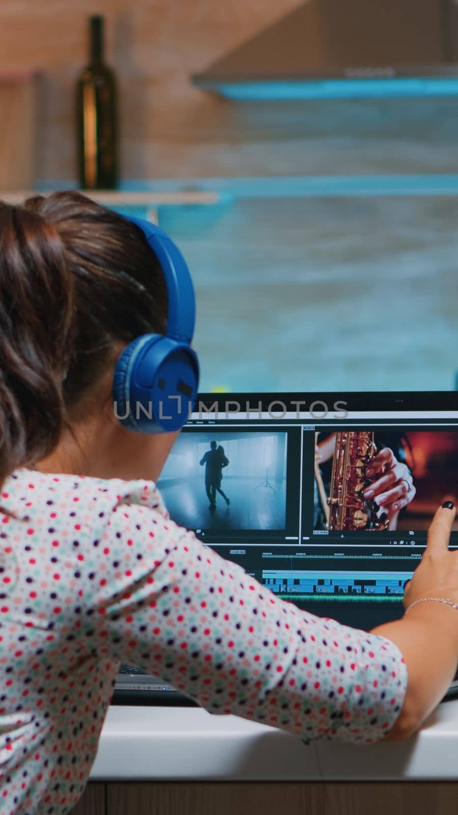 Video editor wearing headset and working from home at digital project sitting in the kitchen. Videographer editing audio film montage on professional laptop sitting on desk in midnight