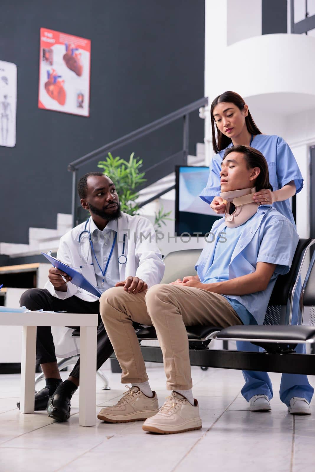 Nurse and traumatologist helping asian patient to take off neck collar while trying to recovery after injury accident during examination. Young adult with cervical foam brace in hospital reception