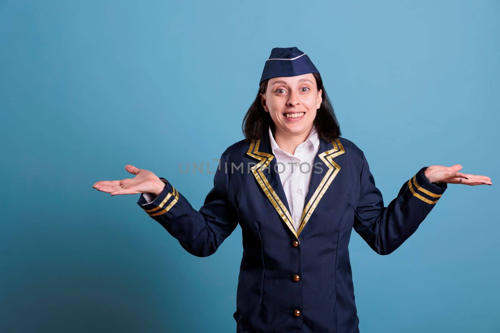 Young confused flight attendant shrugging shoulders by DCStudio