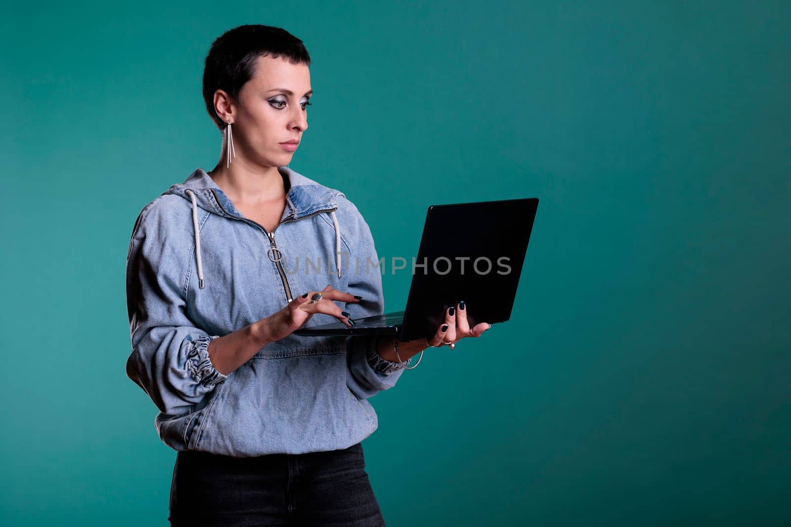 Serious confident woman holding laptop computer having online webinar collaborating with remote colleagues for financial project. Caucasian female typing strategy for business course in studio