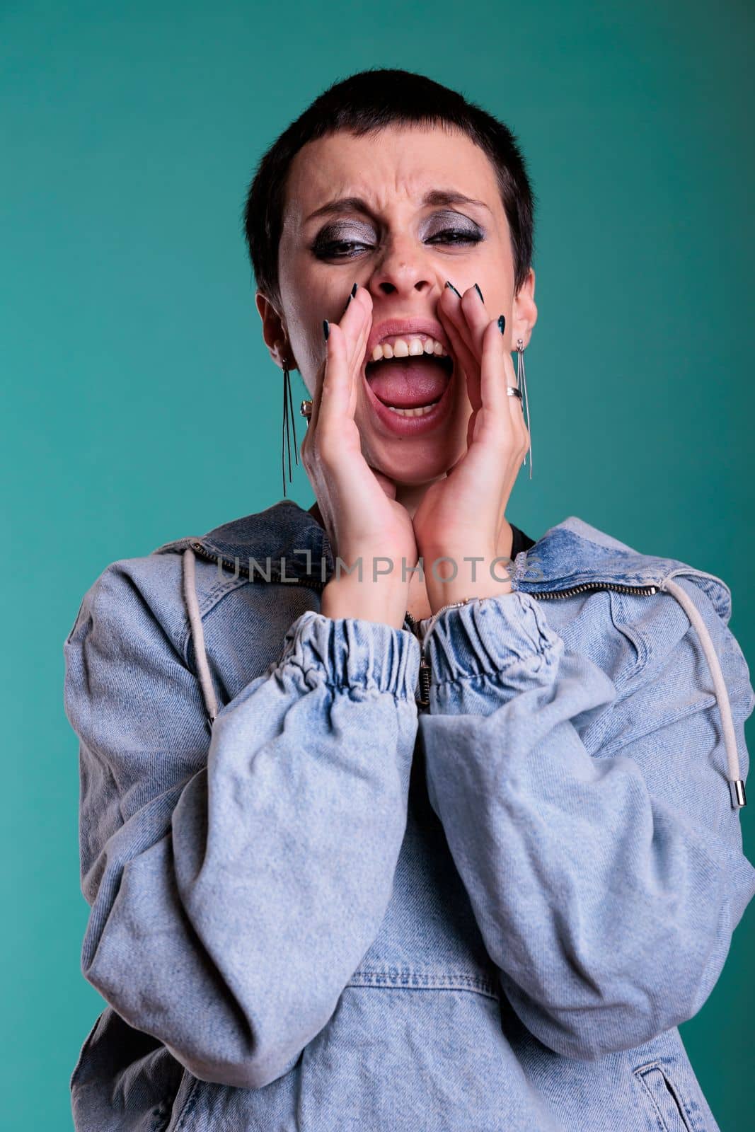 Upset frustrated female aggressively screeming in front of camera while being anger about the news. Stressed person having agressive expression during studio shot standing over isolated background