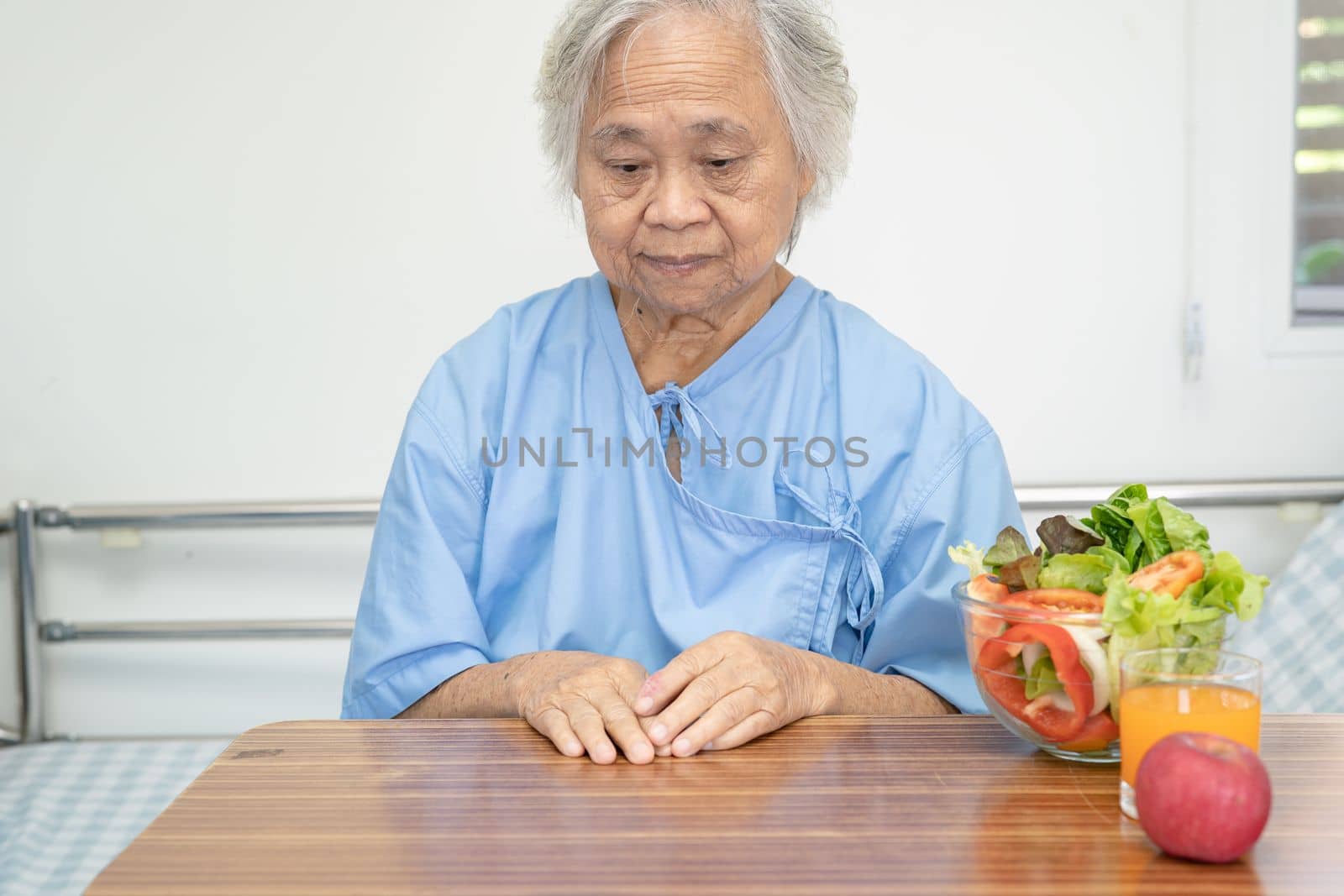 Asian senior or elderly old lady woman patient eating Salmon steak breakfast with vegetable healthy food while sitting and hungry on bed in hospital. by pamai