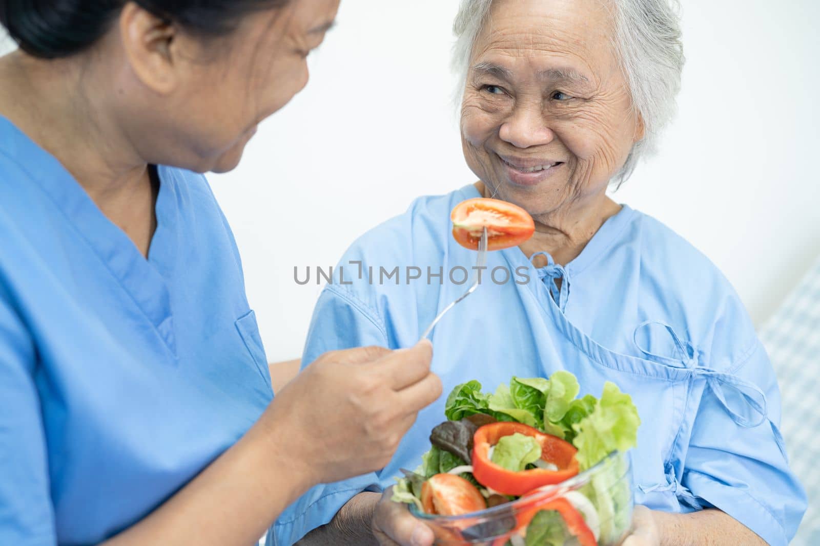 Asian senior or elderly old lady woman patient eating breakfast vegetable healthy food with hope and happy while sitting and hungry on bed in hospital.