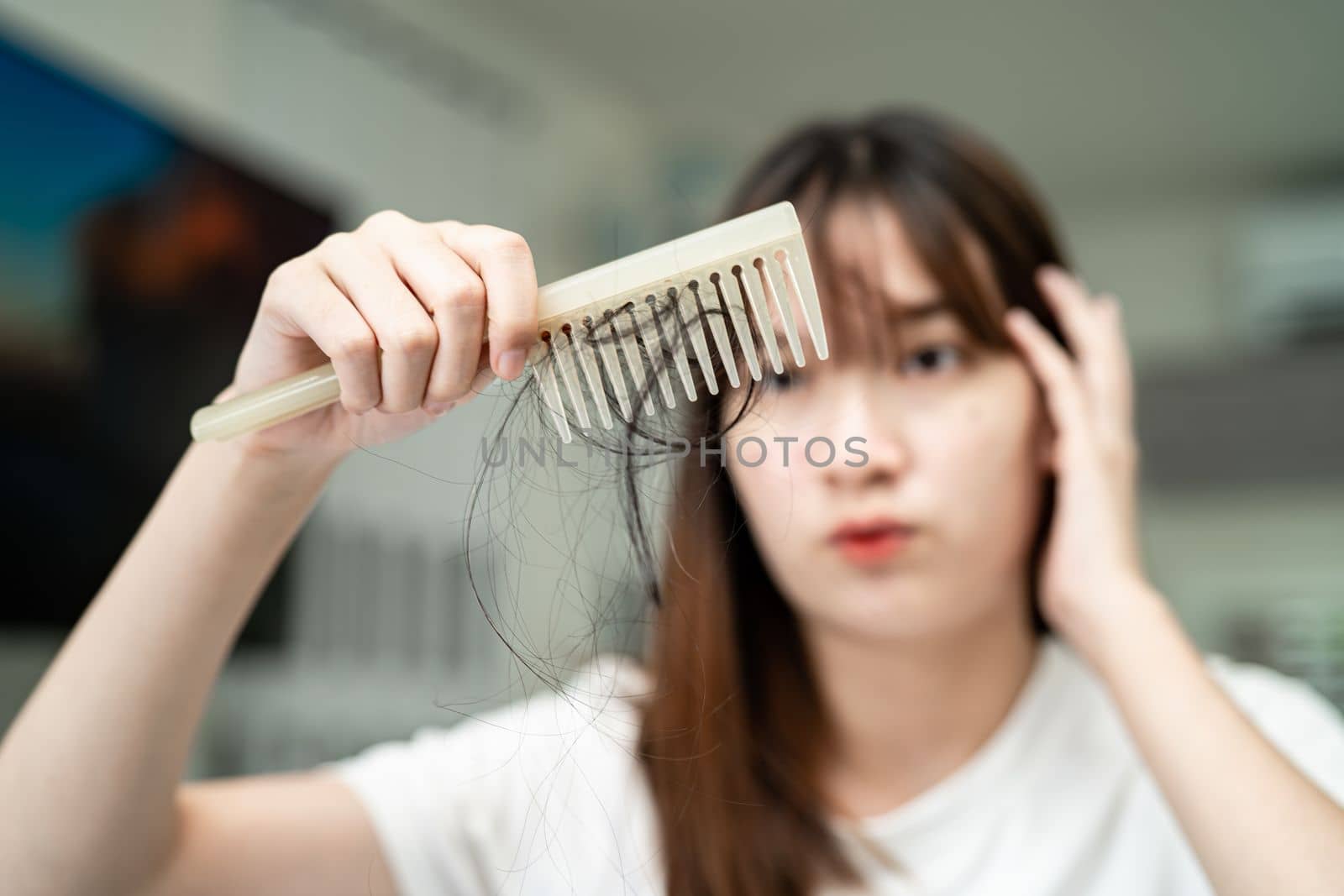 Asian woman have problem with long hair loss attach to comb brush.