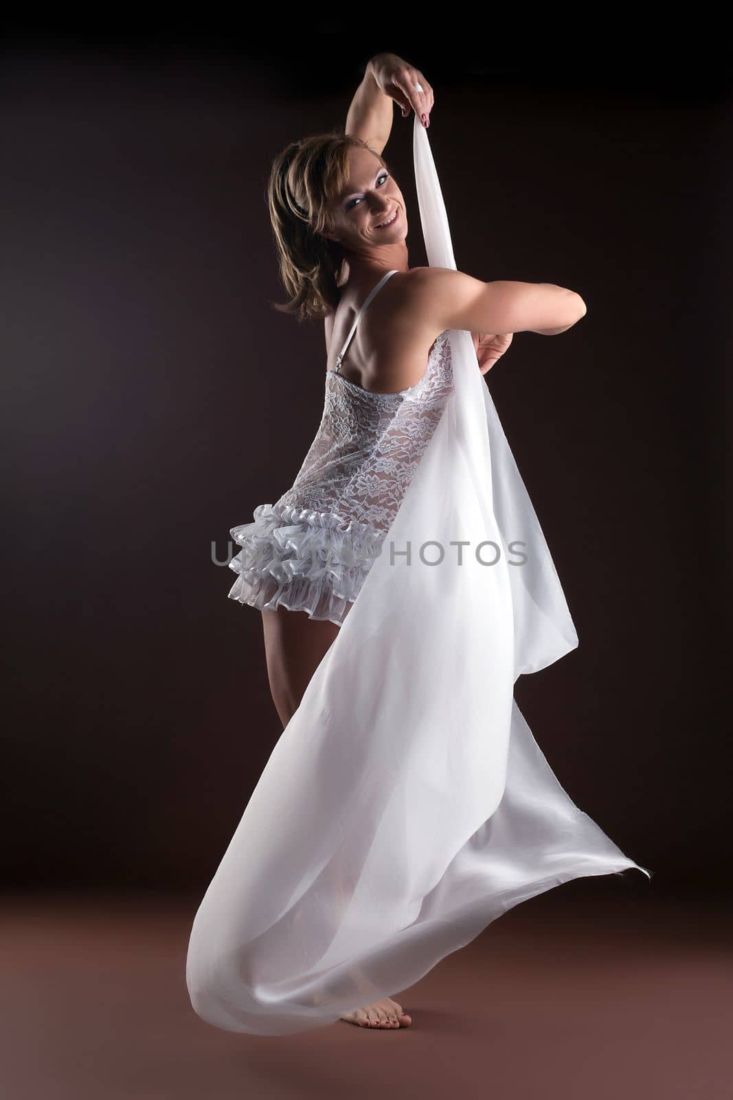 Strong woman body builder in ballet lingerie with flying veil