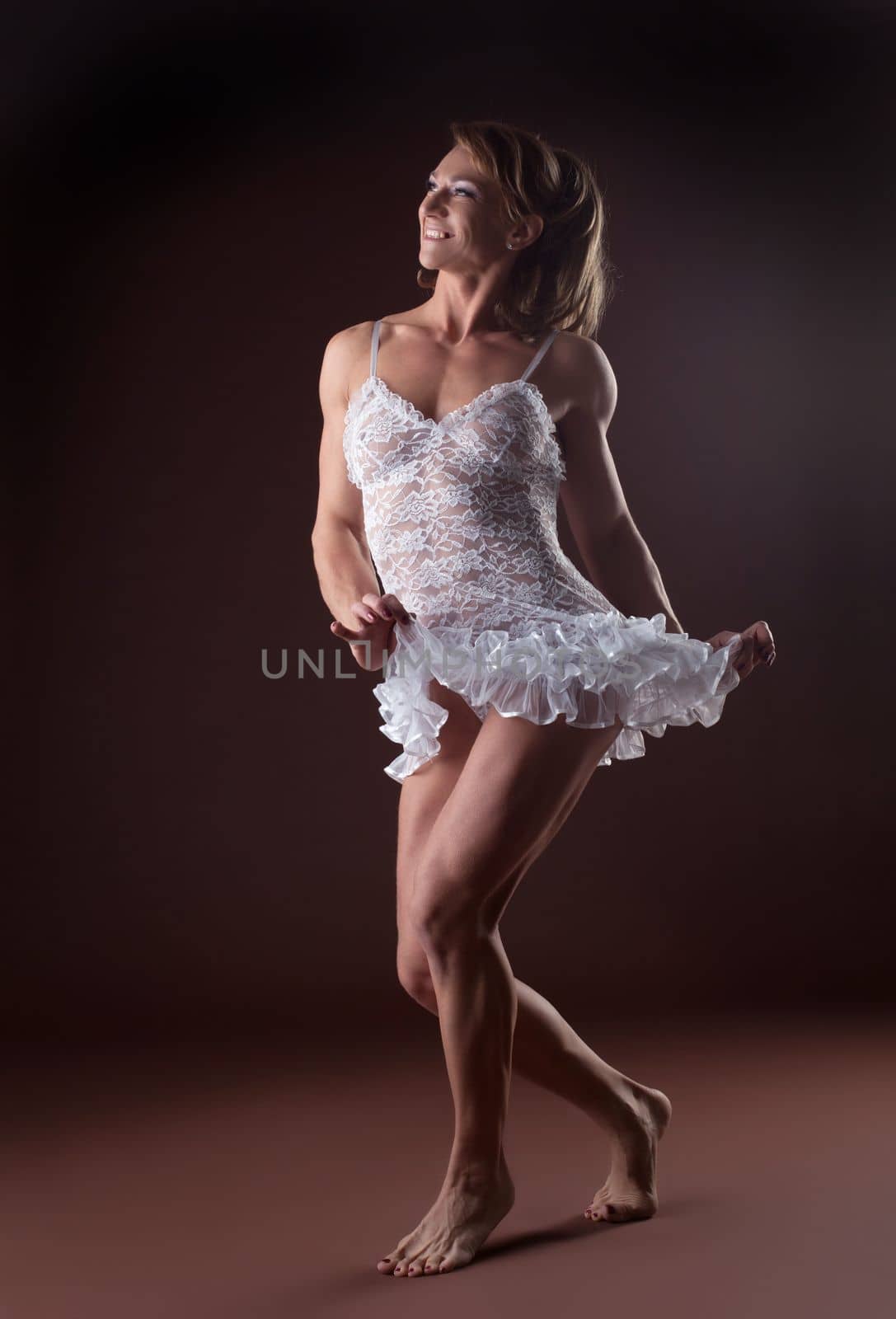 Athletic woman like body builder posing in white ballet cloth