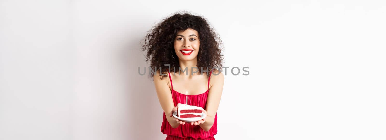 Beautiful woman congratulate with birthday, stretch out bday cake with candle and smiling, standing against white background.