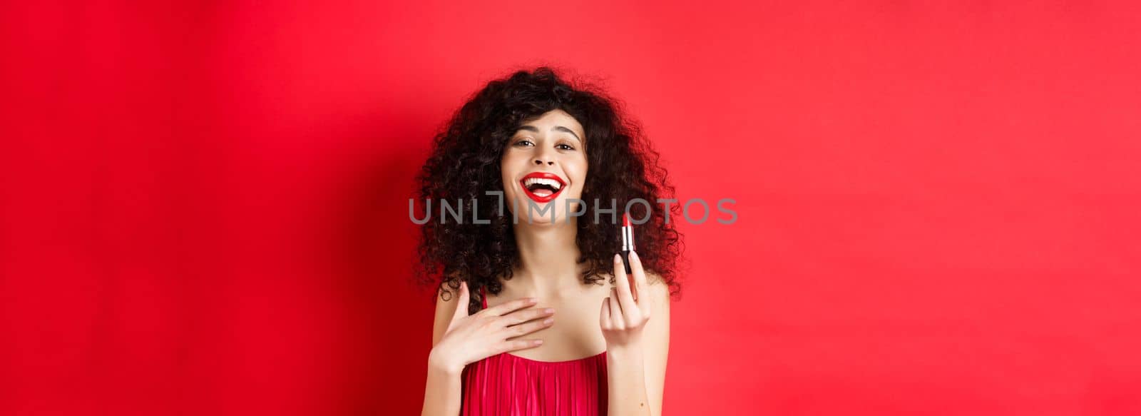 Elegant woman in dress, showing red lipstick and laughing, standing over studio background by Benzoix