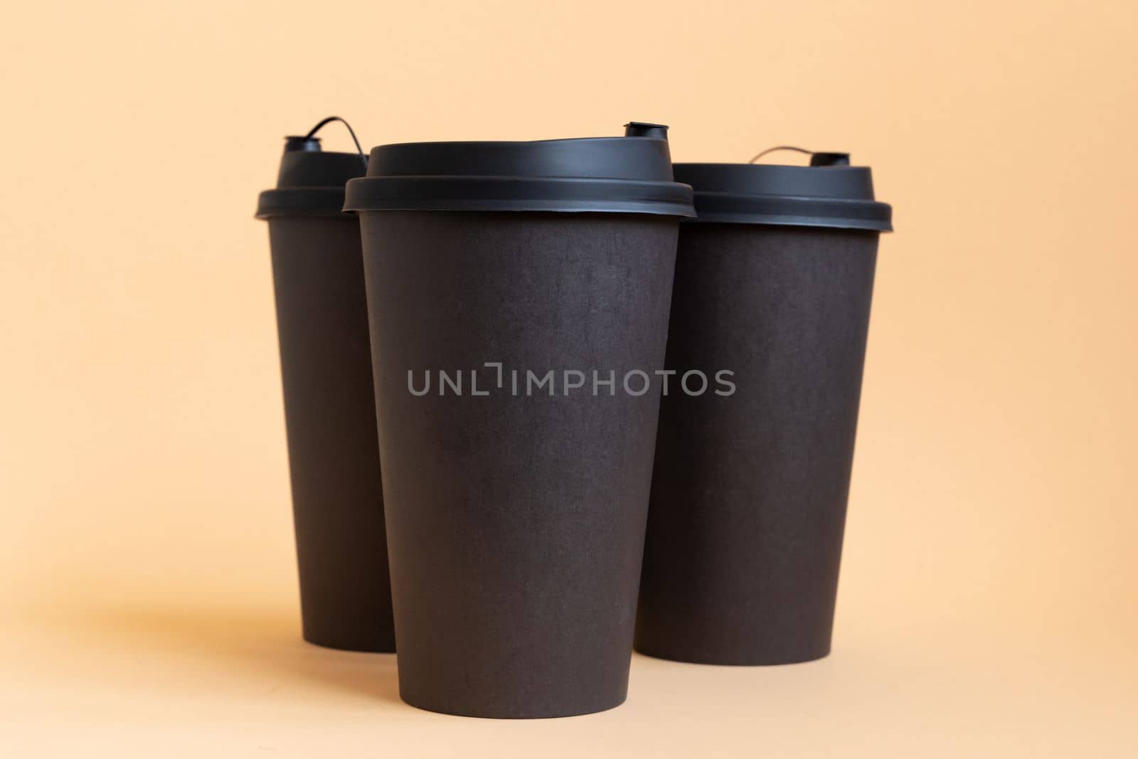 Set of three takeaway black coffee cup on neutral background natural light. Mock -up, nobody, front view by Ri6ka