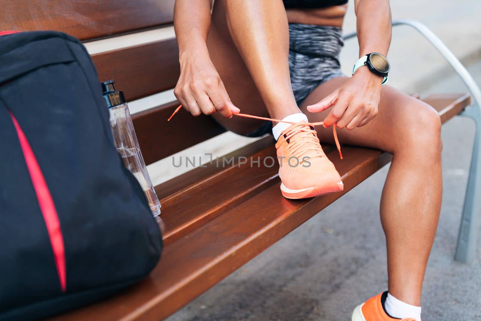 detail of the legs of a sportswoman lacing up her running shoes before her workout, urban sport and healthy lifestyle concept