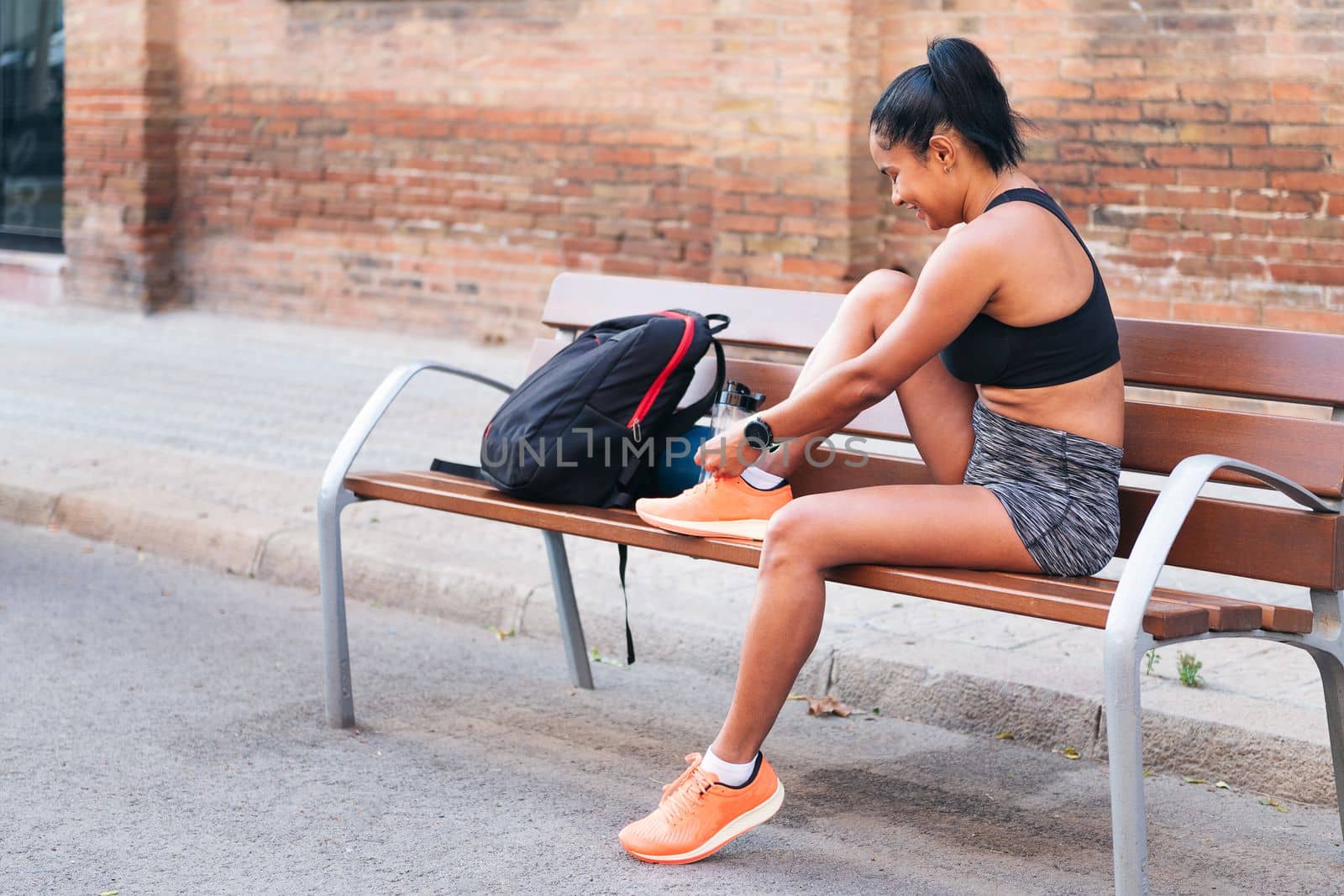 young sportswoman lacing up her running shoes before her workout, urban sport and healthy lifestyle concept, copy space for text
